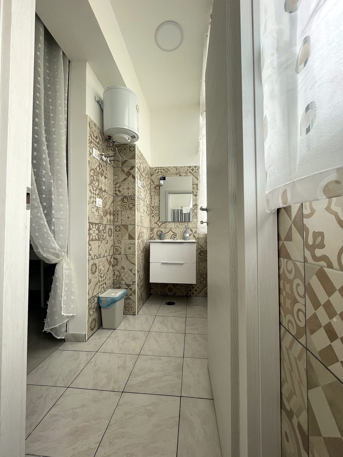 Bagno privato con maioliche decorate e lavabo sospeso, Una Notte a Napoli