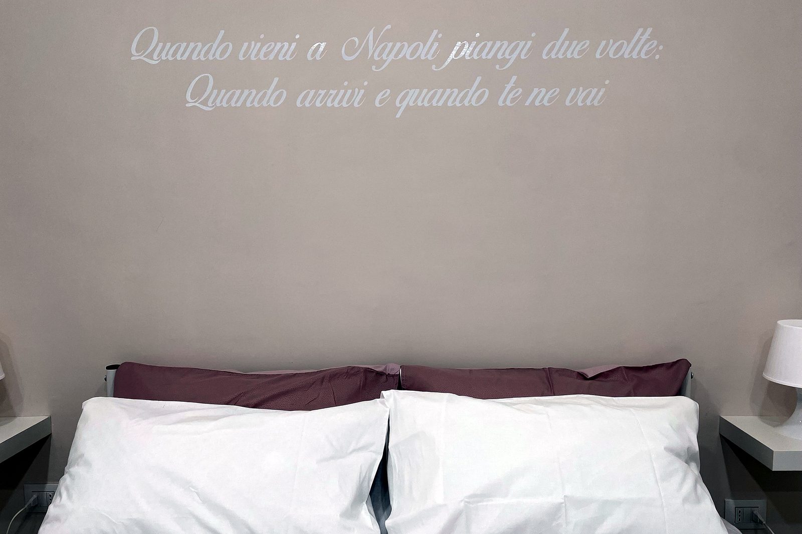 Testata del letto matrimoniale con la scritta napoletana sul muro, Una Notte a Napoli