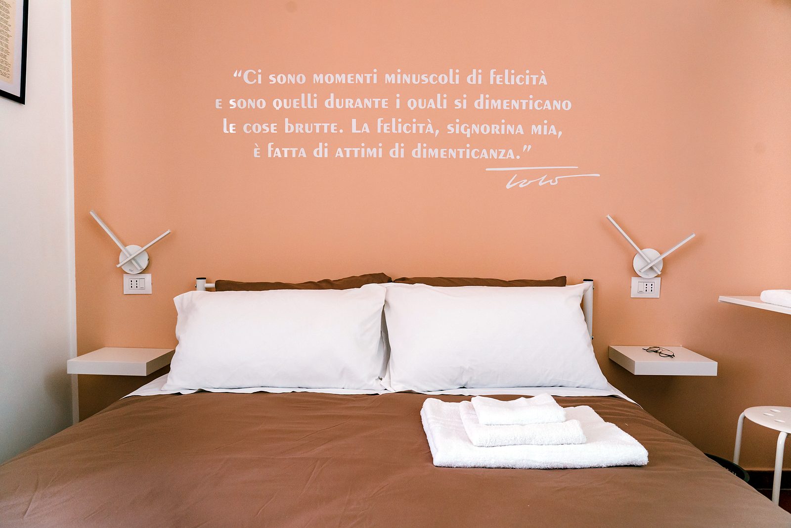 Letto matrimoniale con la frase di Totò sulla parete color pesca, camera Totò, GGGrow Santa Brigida, Napoli centro
