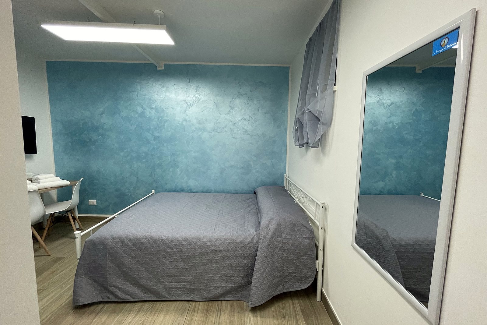 Camera matrimoniale con parete azzurra effetto marino, letto, scrivania e specchio, La Terrazza di Bellavista, Napoli