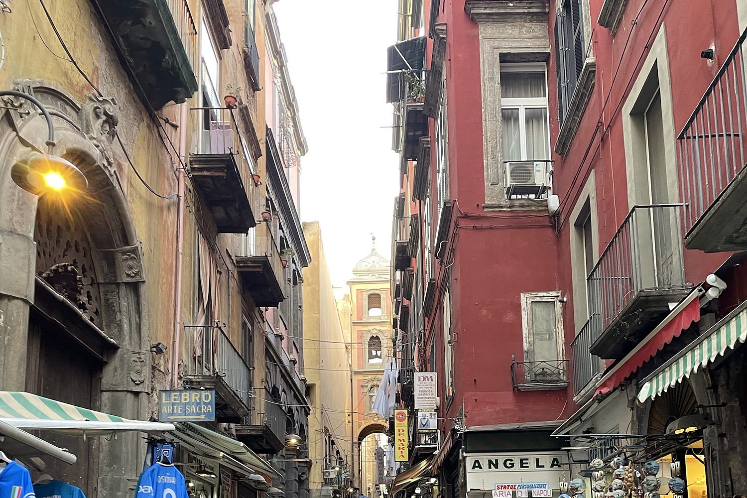 Vicolo del centro storico di Napoli con botteghe e campanile, a pochi passi da Via Duomo